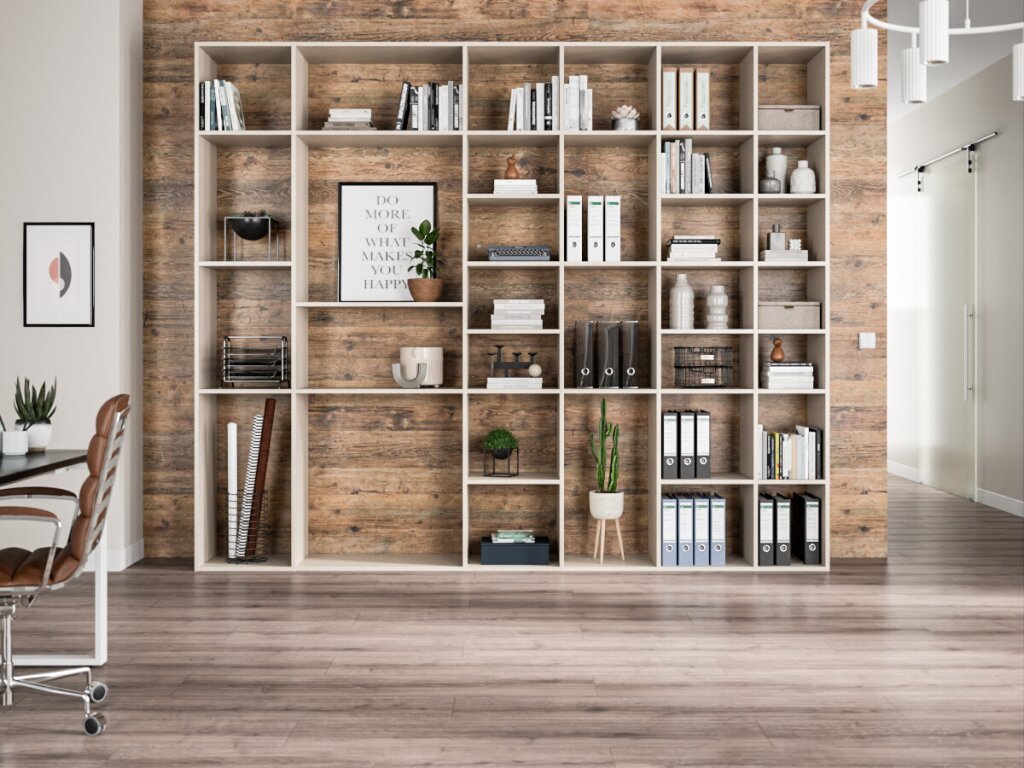 Ein schlichtes, weißes offenes Regal vor einer rustikalen Holzwand. Das Regal bietet Platz für zahlreiche Aktenordner, Pflanzen, Bücher und Dekorationsobjekte. Es vereint Büroutensilien mit stilvoller Dekoration.