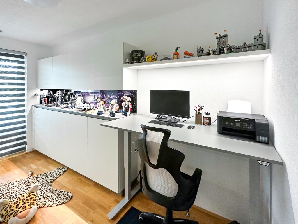 Maßgefertigtes Homeoffice für LEGO Star-Wars-Fans – mit höhenverstellbarem Schreibtisch, viel Stauraum und integrierter Vitrinenfläche für Sammlerstücke, geplant vom Tischler für Funktion und Persönlichkeit.