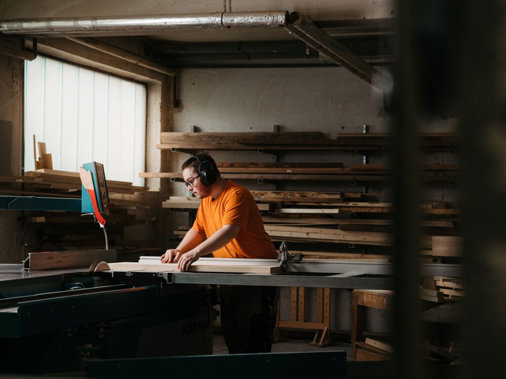 Tischler Marcel arbeitet an der Kreissäge und längt Massivholzpfosten ab. Ein Sinnbild für maßgefertigte Küchenplanung vom Tischler.