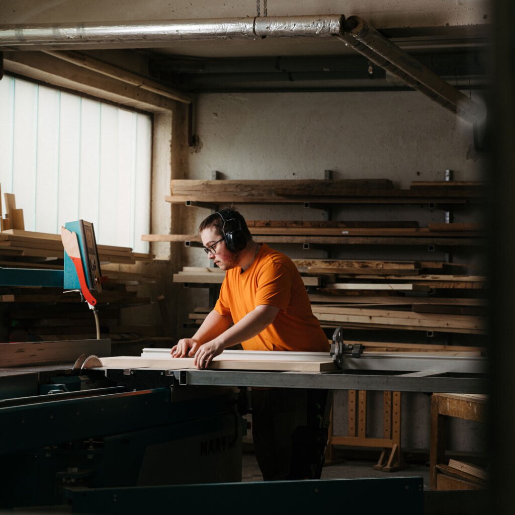 Tischler Marcel arbeitet an der Kreissäge und längt Massivholzpfosten ab. Ein Sinnbild für maßgefertigte Küchenplanung vom Tischler.