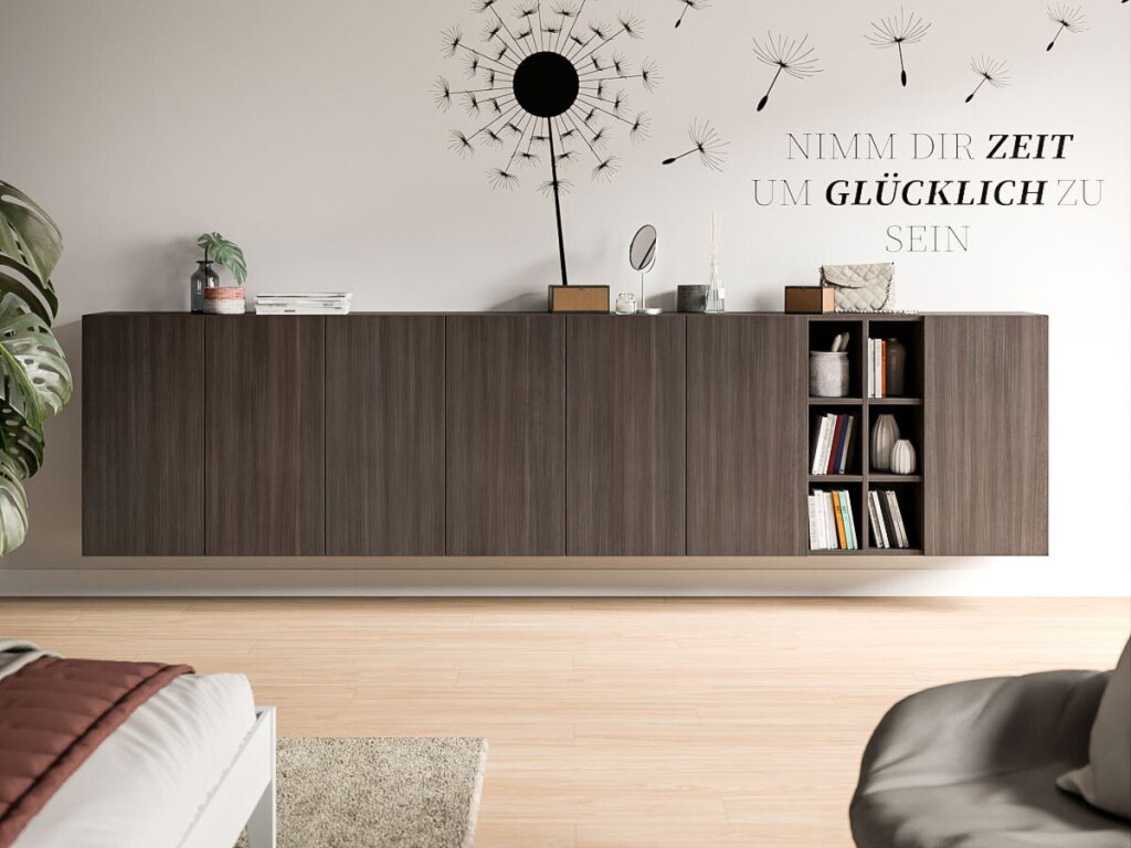 Ein großes Sideboard hängt an einer weißen Wand, die mit einem Sinnspruch bemalt ist: "Nimm dir die Zeit um glücklich zu sein". Das Sideboard wurde aus dunklem Holzdekor gearbeitet und besteht aus acht Segmenten, sieben davon sind geschlossene Drehtüren, ein Segment ist offen als kleines Regal in sich in sechs Fächer unterteilt. Auf dem Sideboard stehen Schminkutensilien, eine kleine Handtasche und ein Bücherstapel, im offenen Segment sind Bücher und Vasen verstaut. Ein angeschnittenes Bett, ein Sessel und eine Zimmerpflanze deuten auf ein Jugendzimmer hin. Die Atmosphäre wirkt aufgeräumt schlicht.