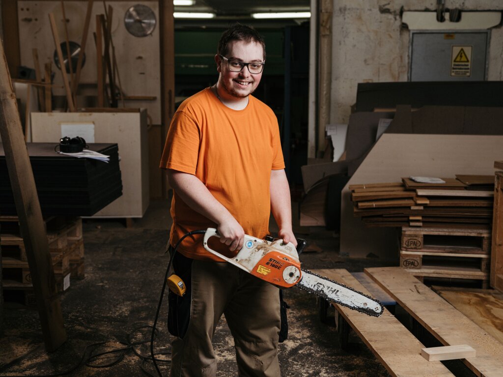 Tischler macht sich bereit mit der Motorsäge Naturholz zu schneiden.