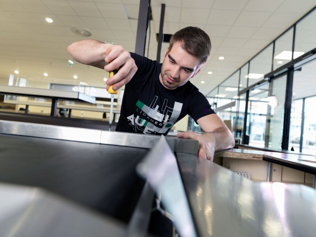 Monteur im Ladenbau bei der Montage eines Kassenbandes.